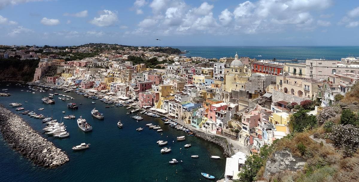 A curve of tall pastel fishermen’s houses stacked above a small harbour of boats