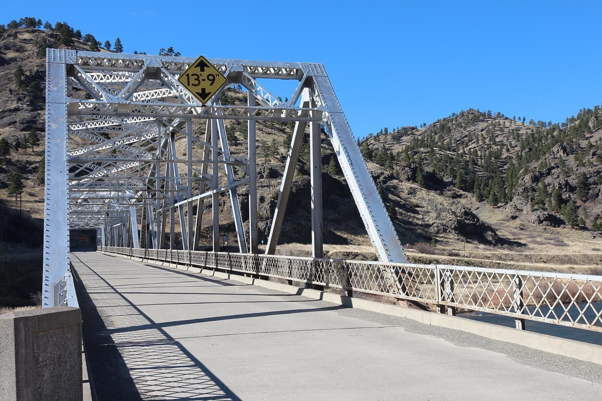 A steel truss bridge over a wide river in open country
