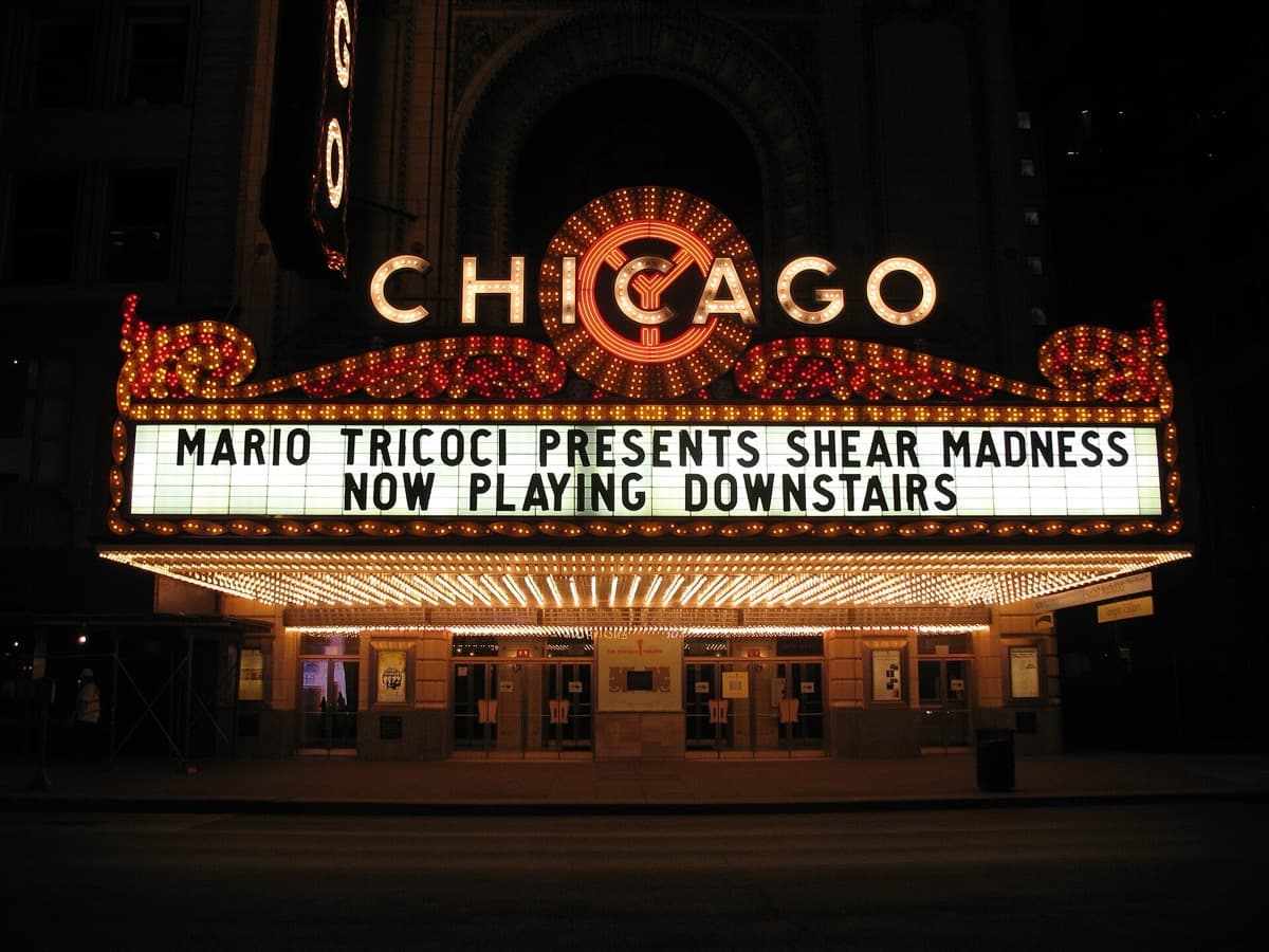 A tall lit vertical sign reading Chicago above a theatre front