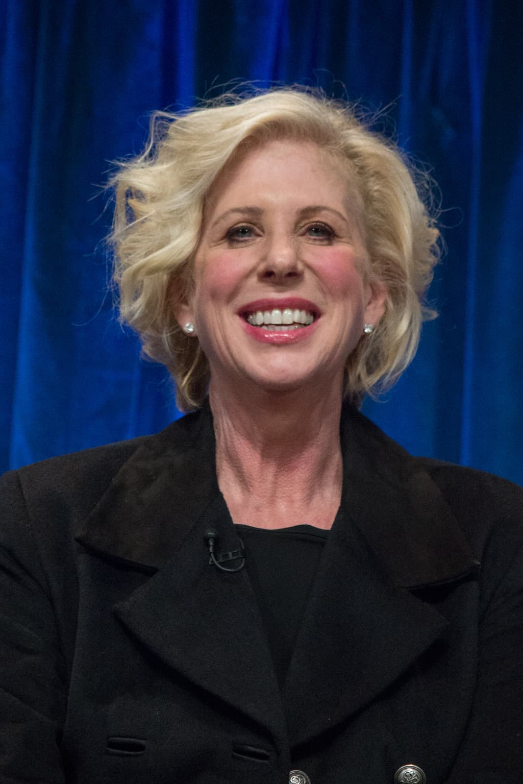 Callie Khouri smiling, short blonde hair, dark coat