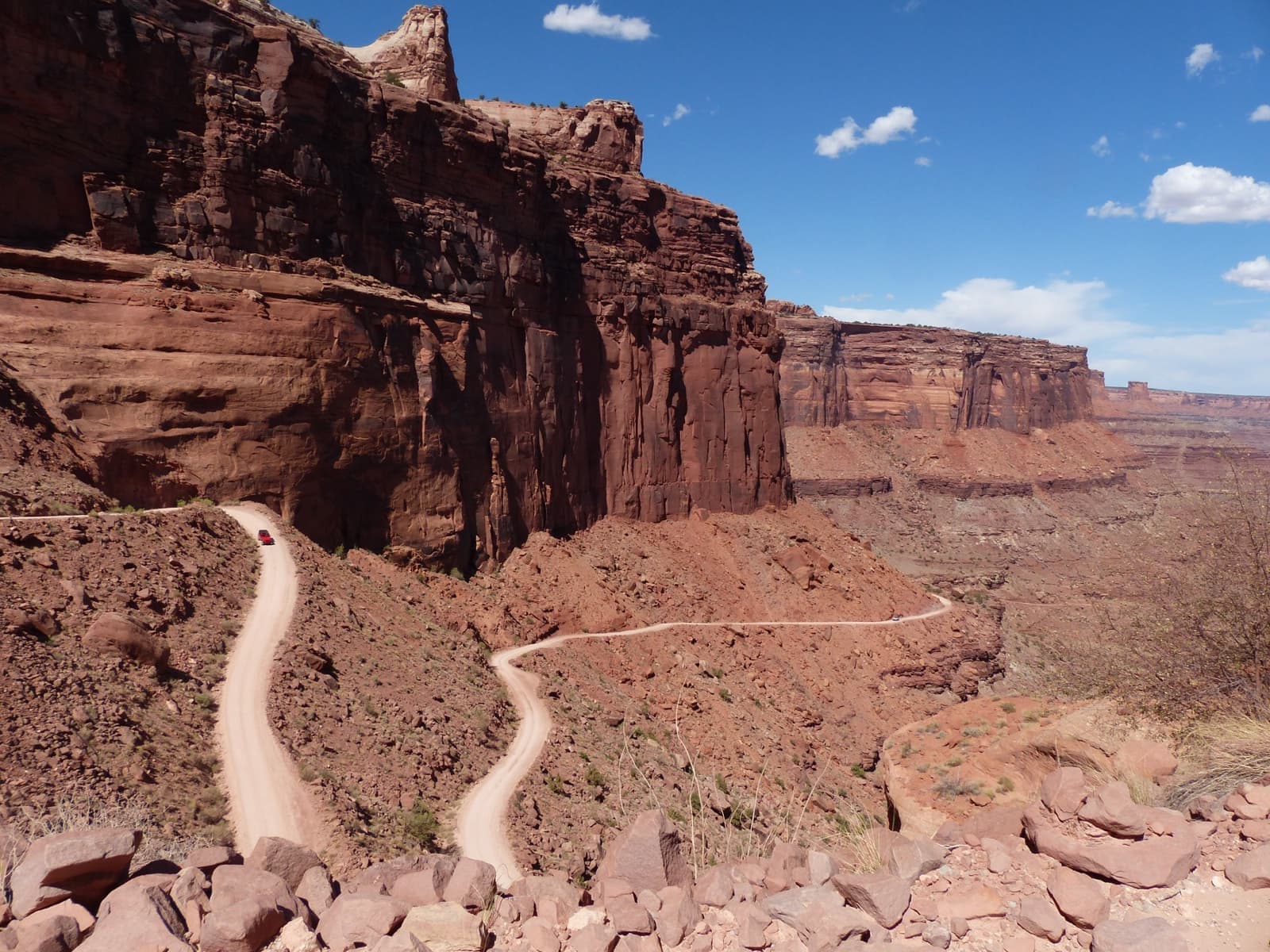 A dirt road zigzagging down a red canyon wall