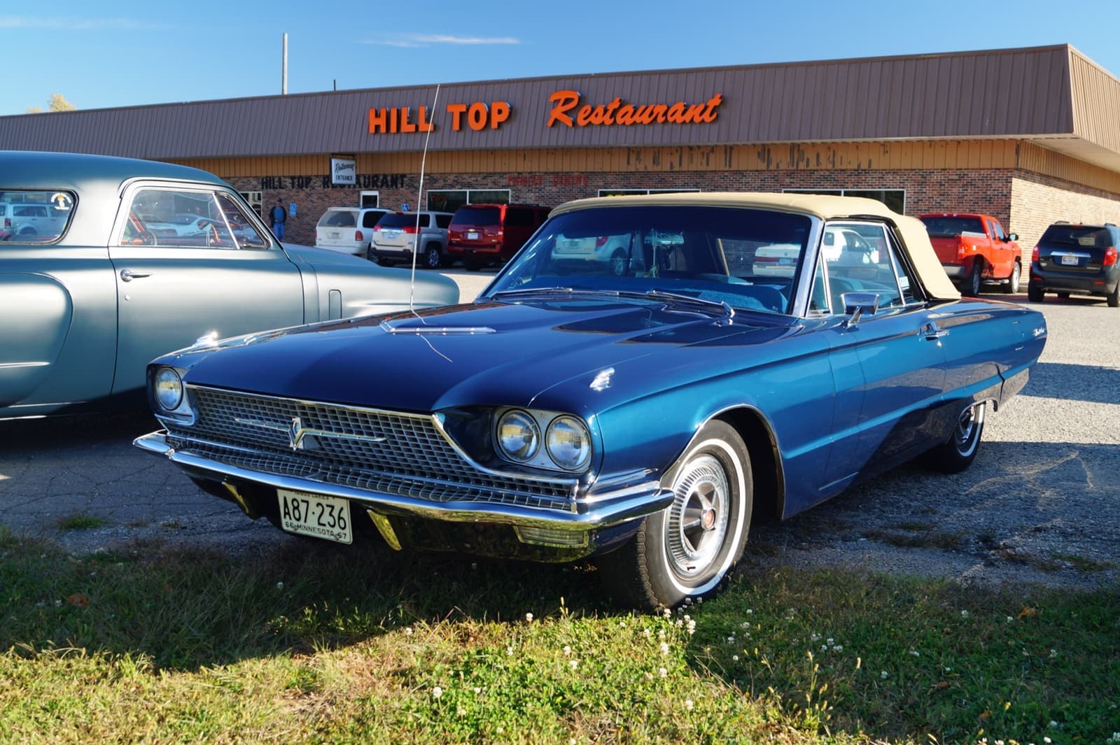 A blue 1966 Thunderbird convertible parked in front of a roadside restaurant