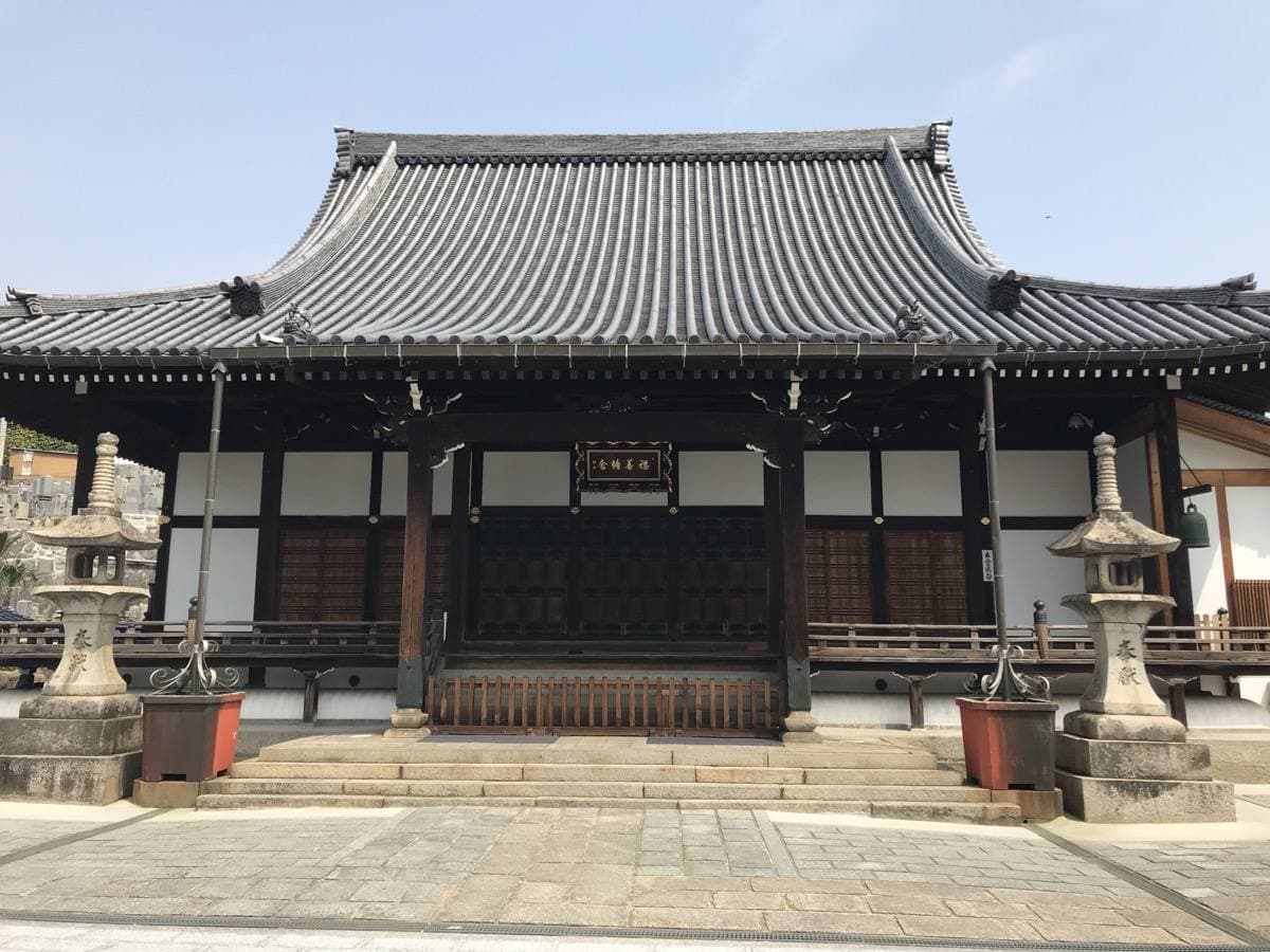 A broad tiled temple hall with stone lanterns either side of the steps