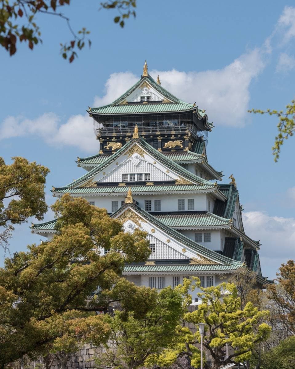A white and green castle keep with gold trim above trees