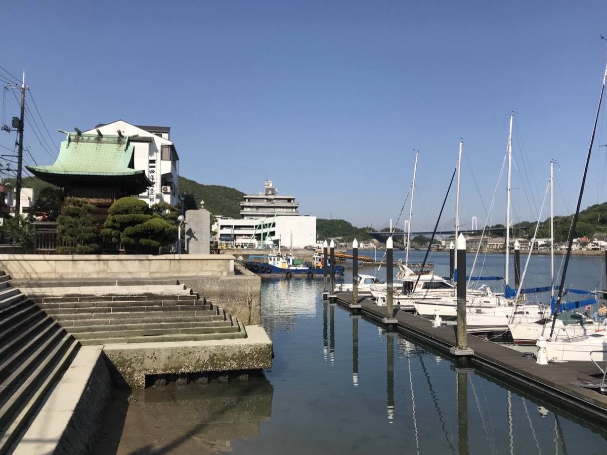A small shrine roof beside a marina of moored yachts on a calm channel