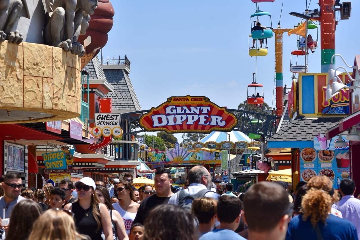 Rides and sign towers of a seaside boardwalk under a bright sky