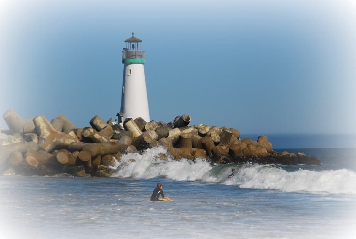 A small white lighthouse at the edge of a beach