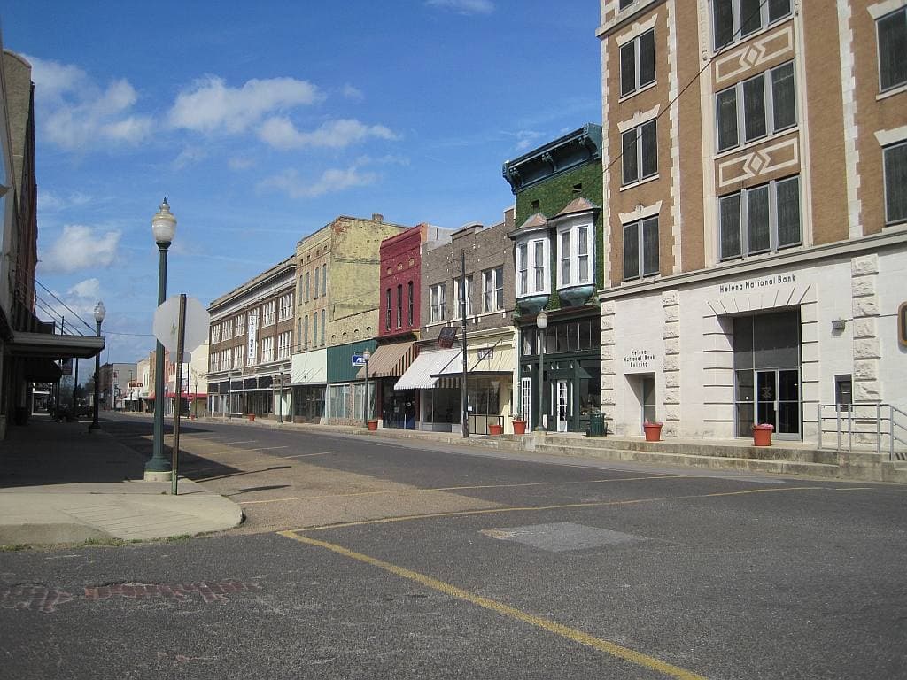 An empty main street of brick shopfronts and an old bank building under a blue sky
