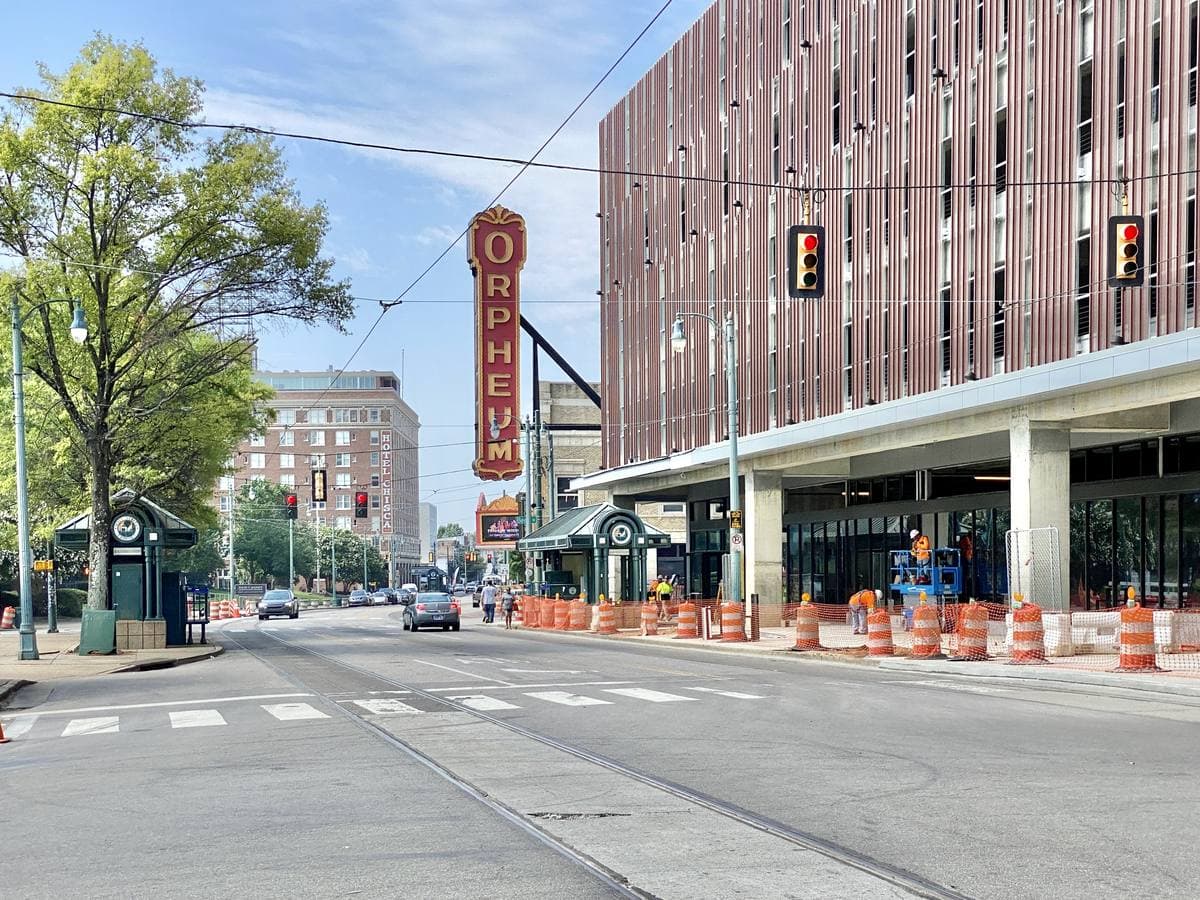 A tall vertical theatre sign reading ORPHEUM above a wide downtown street with a trolley line