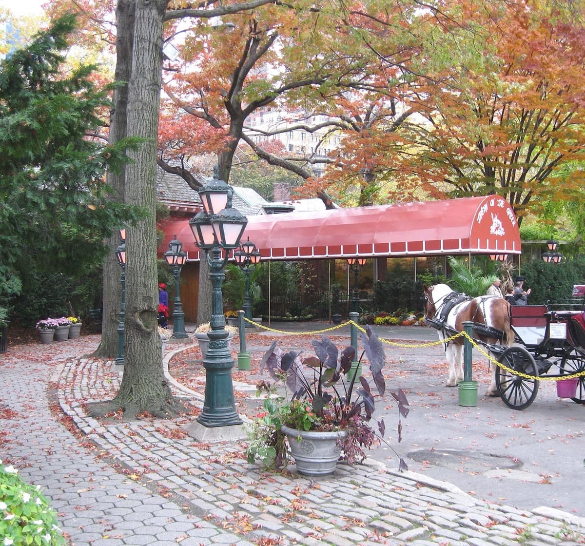A glass canopy over the entrance of a brick Victorian building in a park