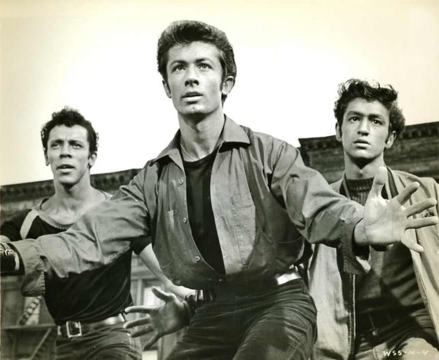 Three young men mid-stride, arms out, George Chakiris in the centre