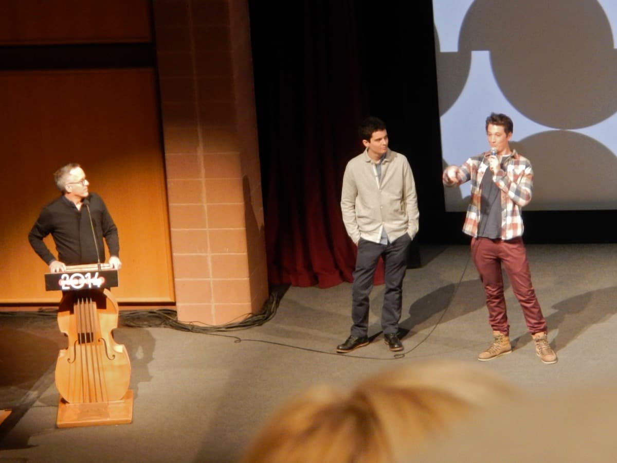 Three men standing together indoors at a festival event