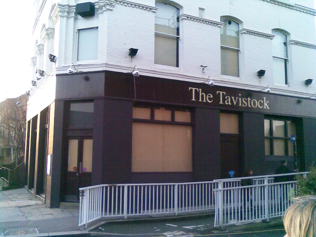 A corner pub building with a painted sign on a quiet street