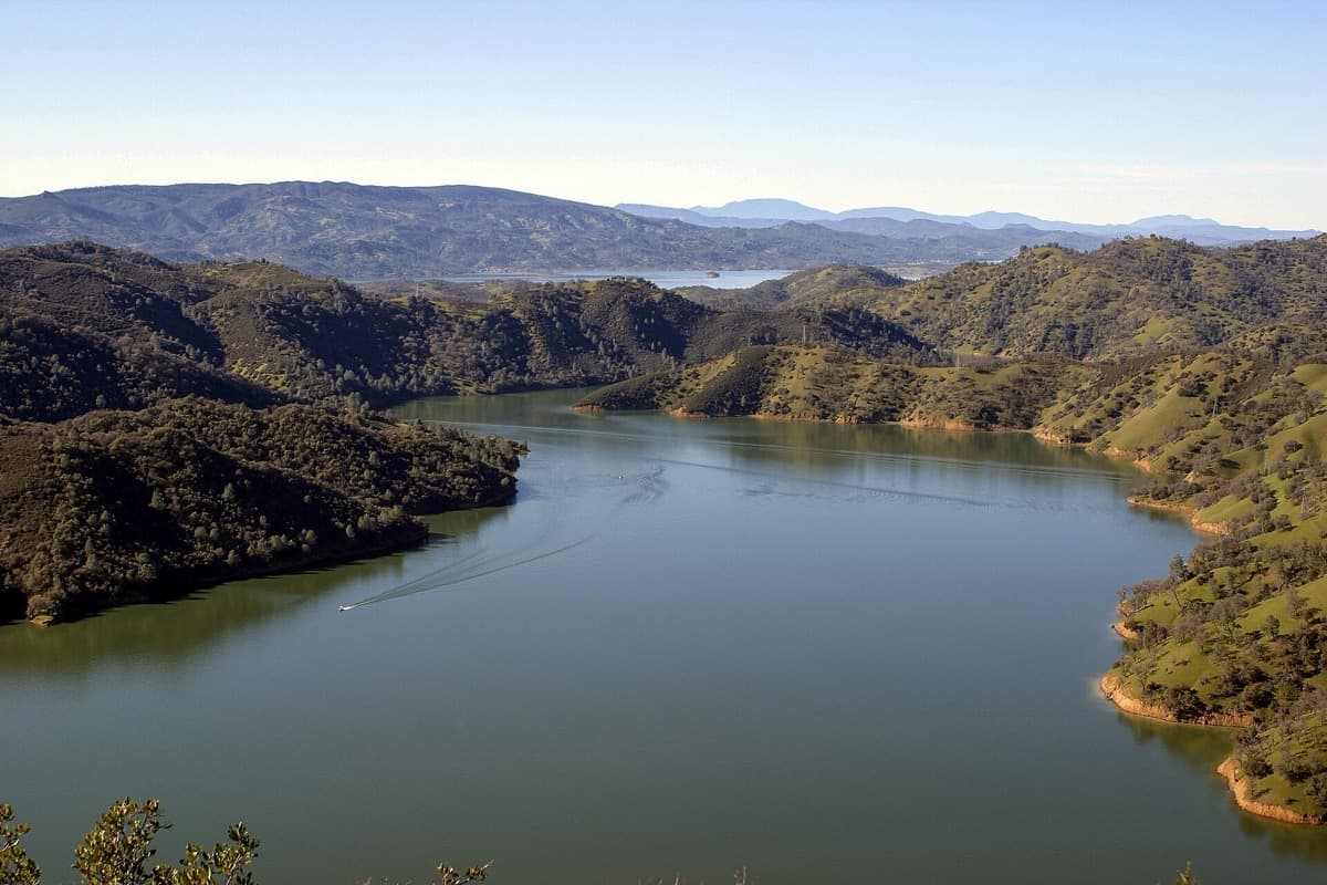 A wide reservoir among dry brown hills under a pale sky