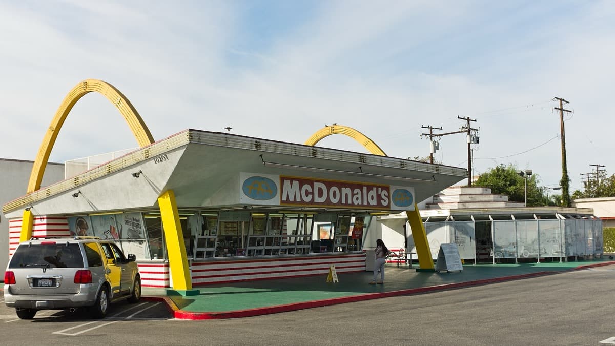 A 1950s roadside building with a tall sign under a bright sky