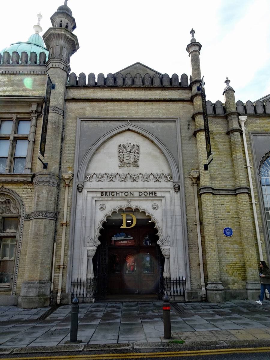 An ornate cream archway with minarets over a dark entrance, a round plaque on the wall beside it