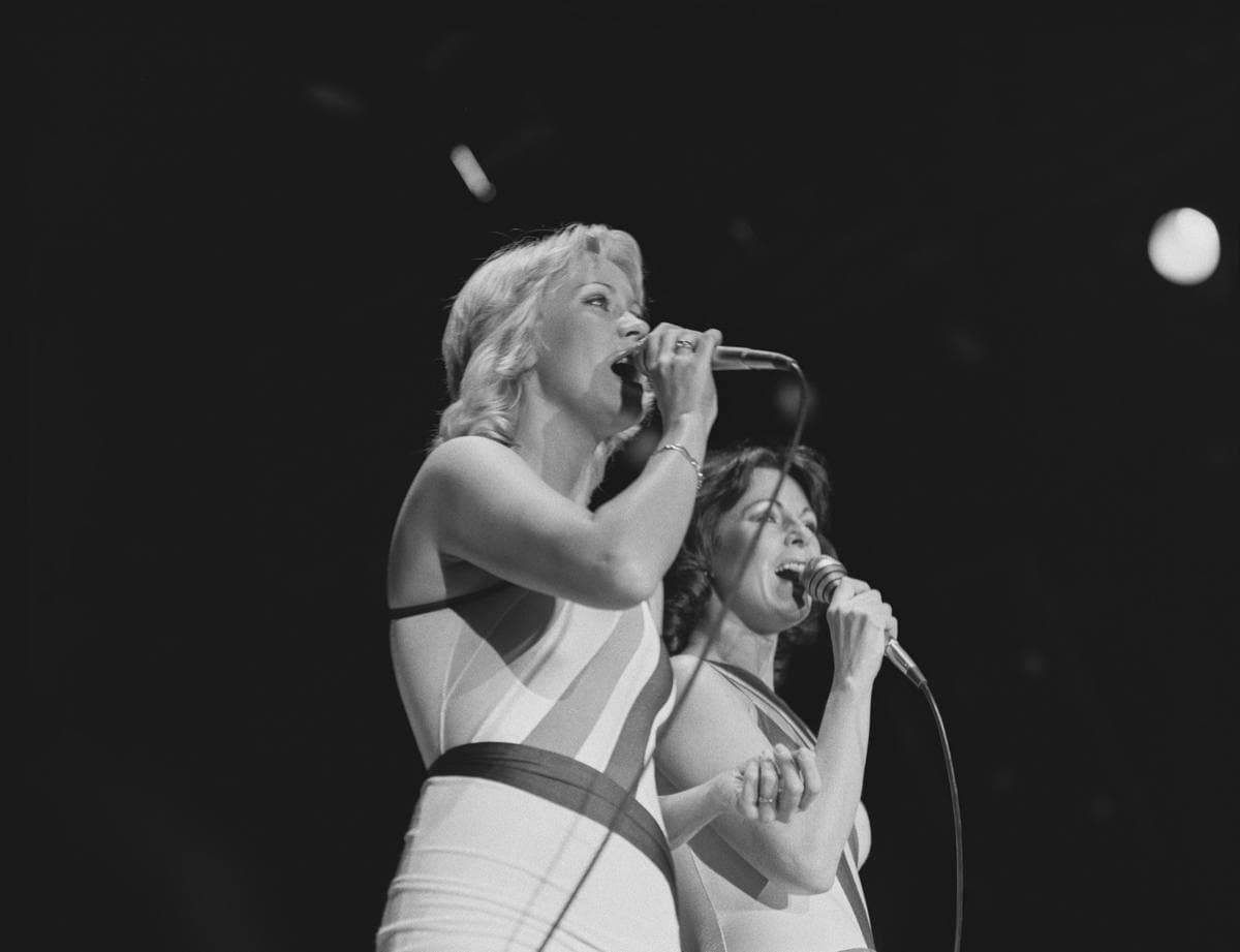 Agnetha Fältskog and Anni-Frid Lyngstad singing side by side in close-fitting stage costumes
