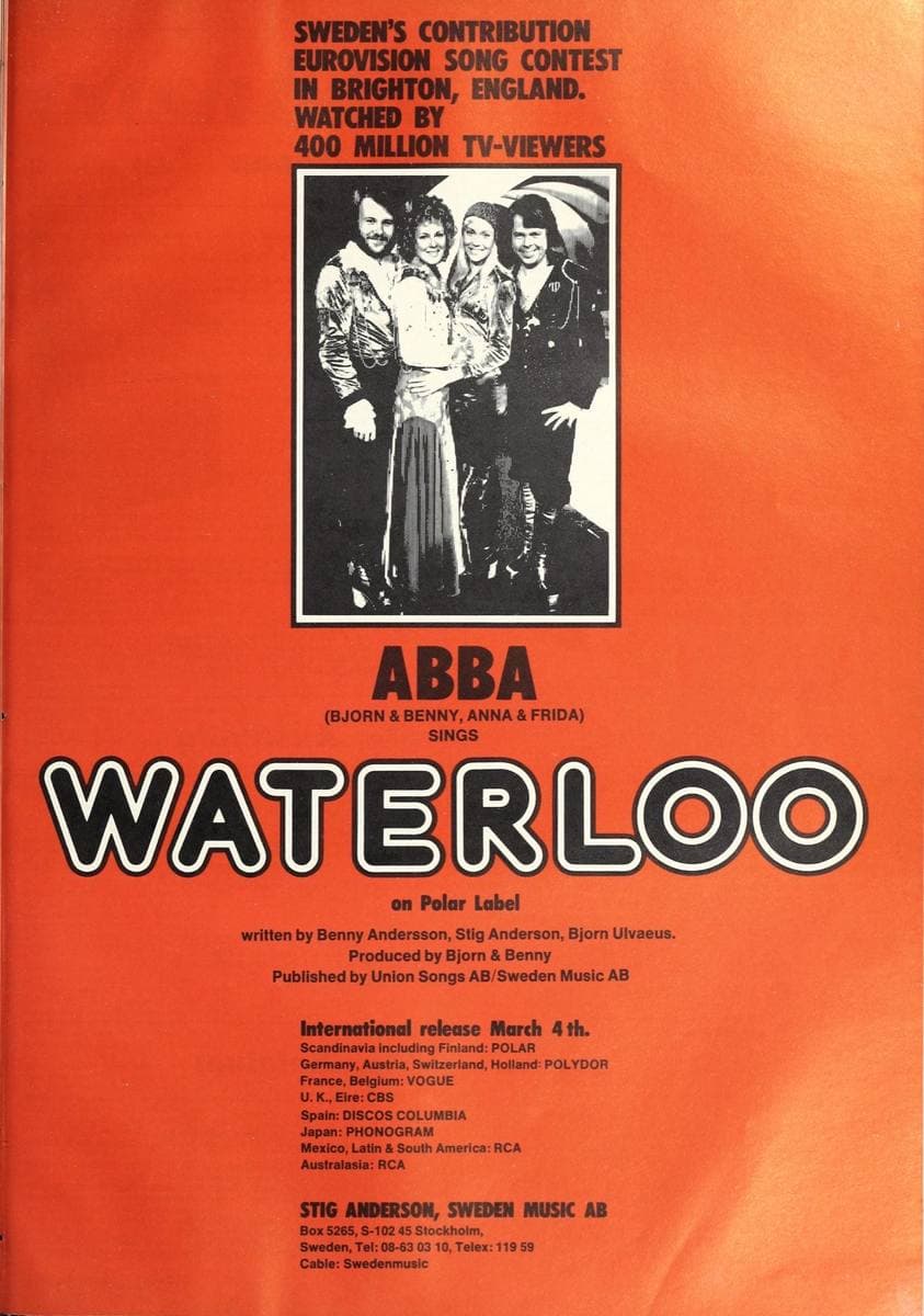 An orange magazine page with a black-and-white photograph of the four members above large outlined lettering