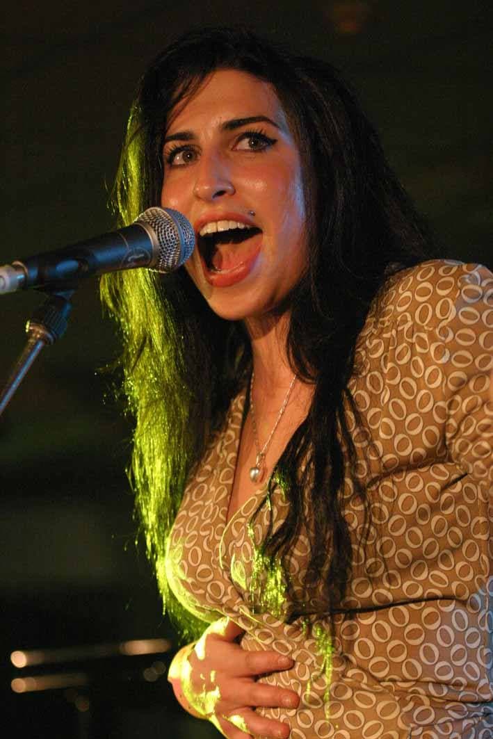 Amy Winehouse singing into a microphone on stage in 2004