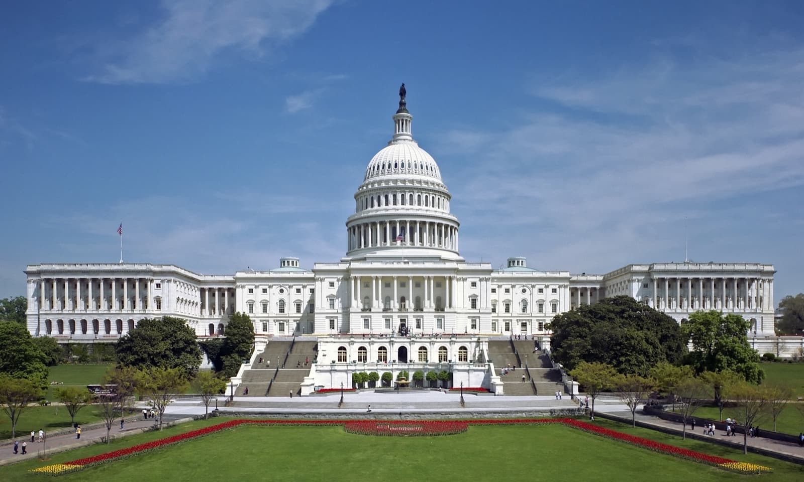 The white dome and West Front of the United States Capitol under a blue sky