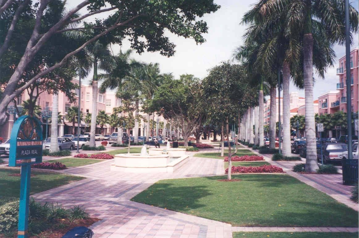 A palm-lined plaza with pastel buildings under a blue sky