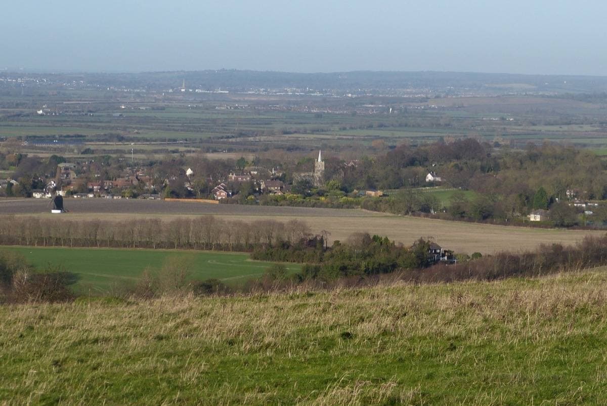A village with a church tower in a green valley seen from a hill
