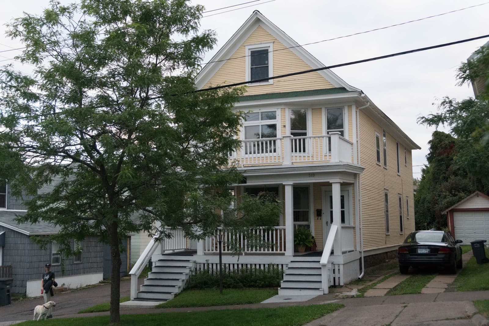 A pale two-storey duplex on a hillside street