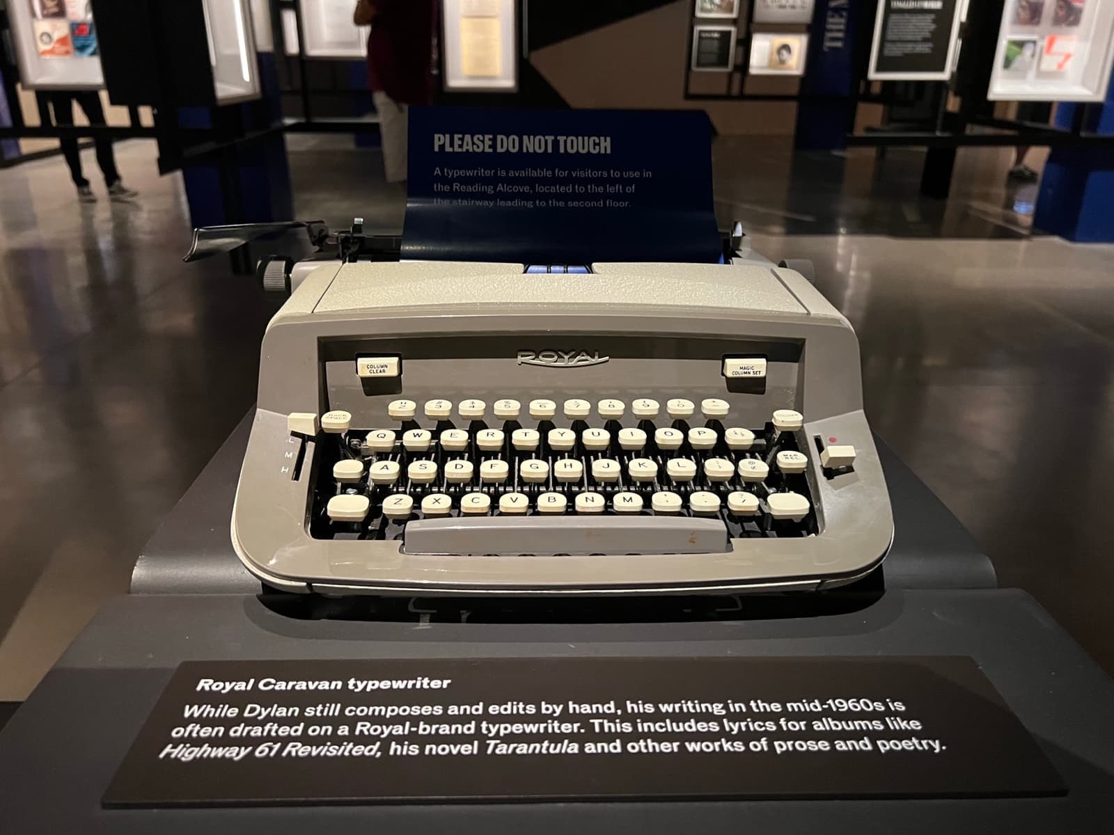 A grey portable typewriter in a museum case