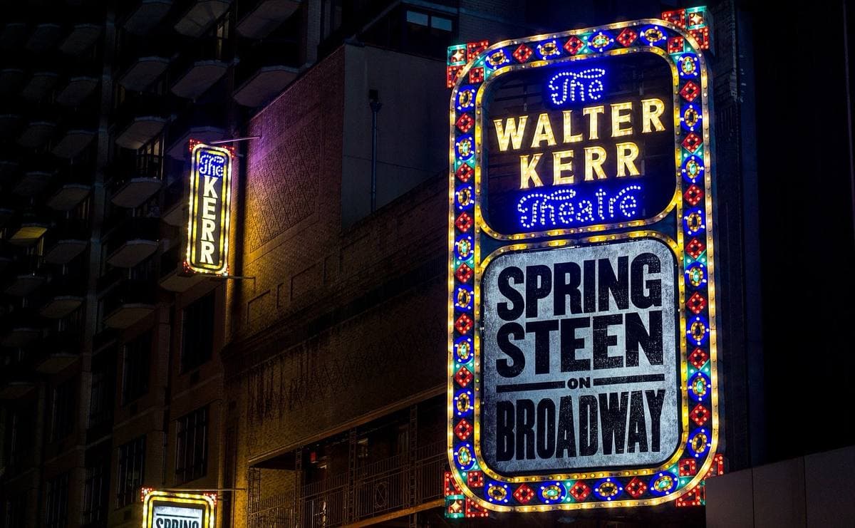 A lit vertical theatre sign reading Walter Kerr Theatre above a panel reading Springsteen on Broadway, at night