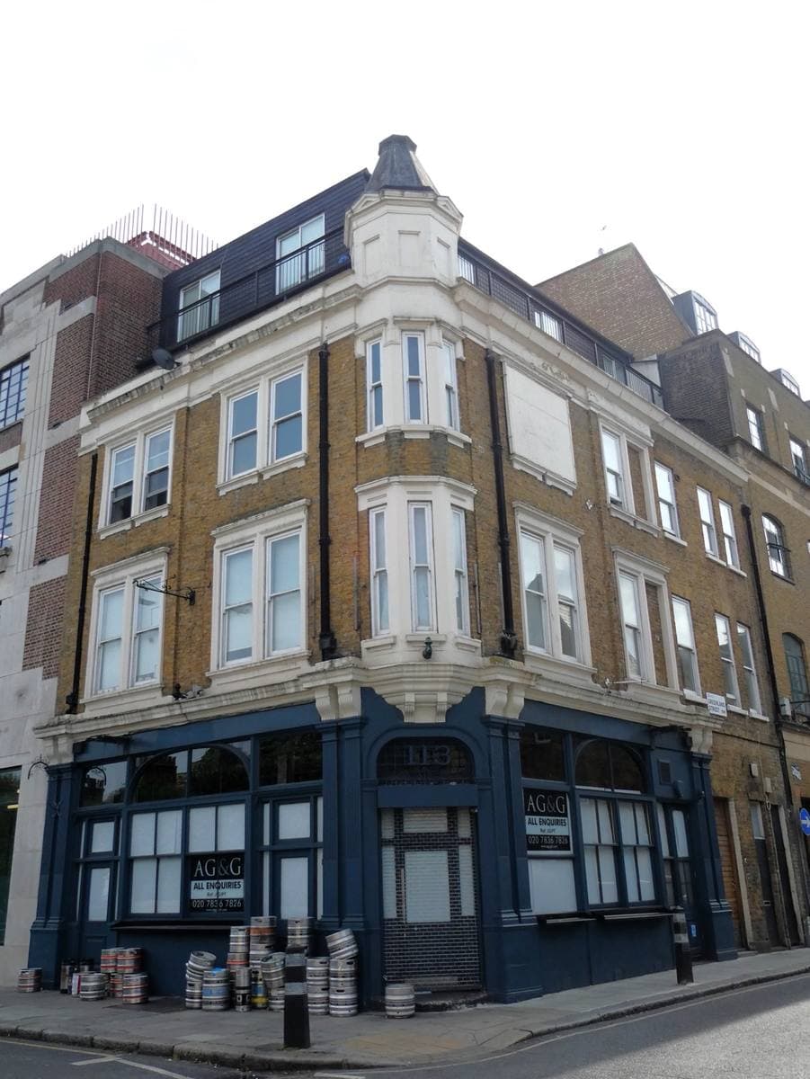 A corner building with a dark blue ground floor, its signs taken down
