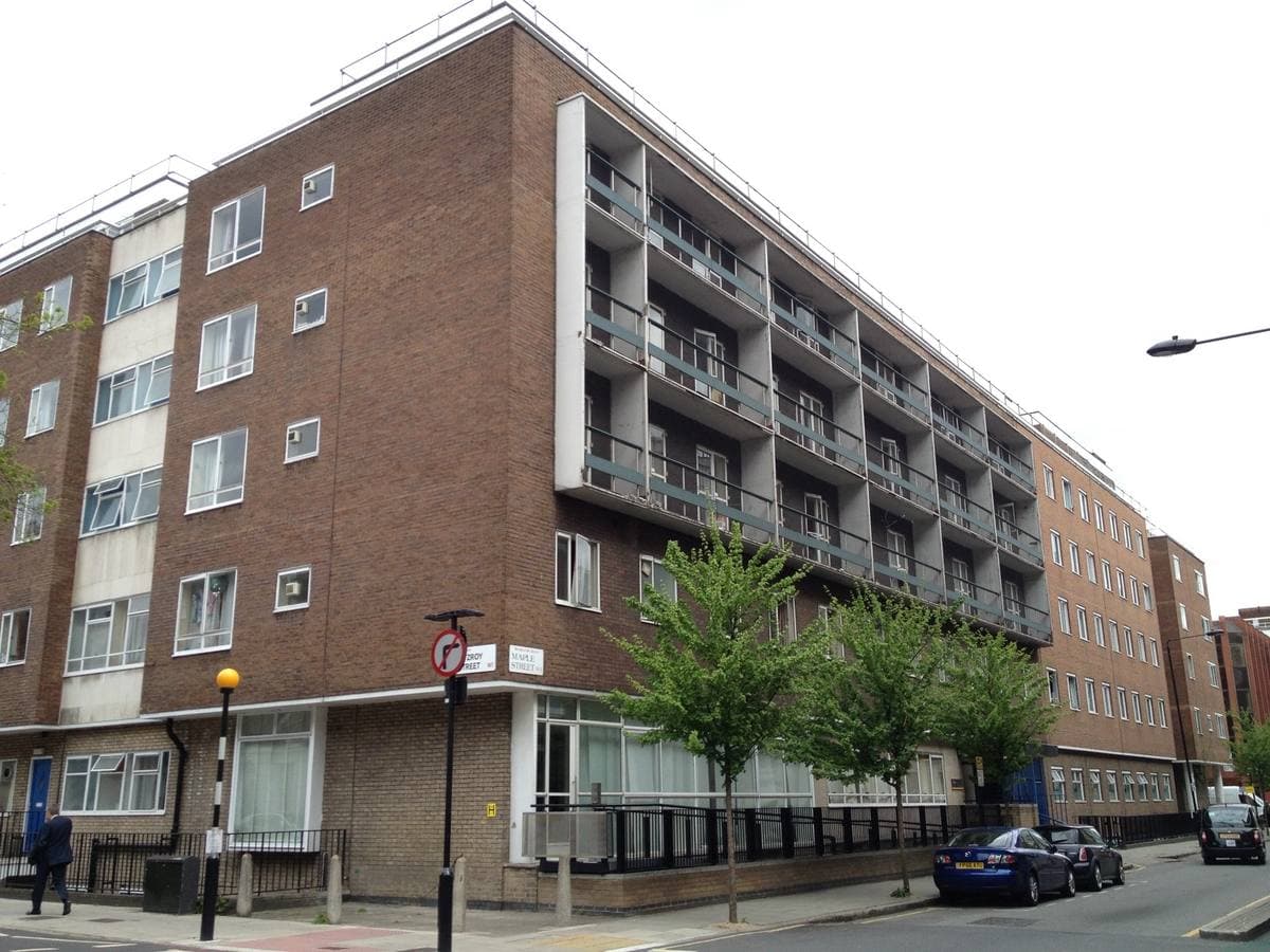 A six-storey brick and concrete block of student rooms with balconies on a street corner