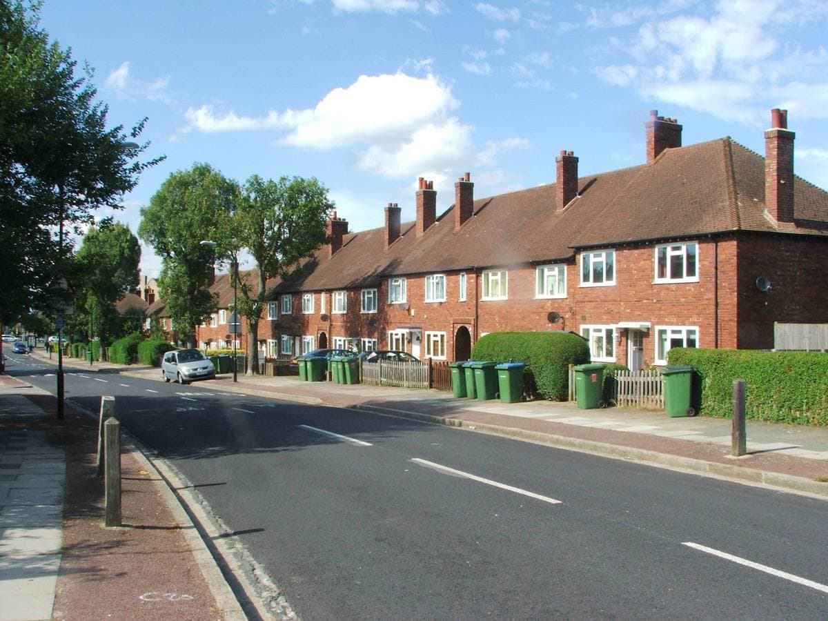 A tree-lined suburban road of brick terraced houses in Eltham