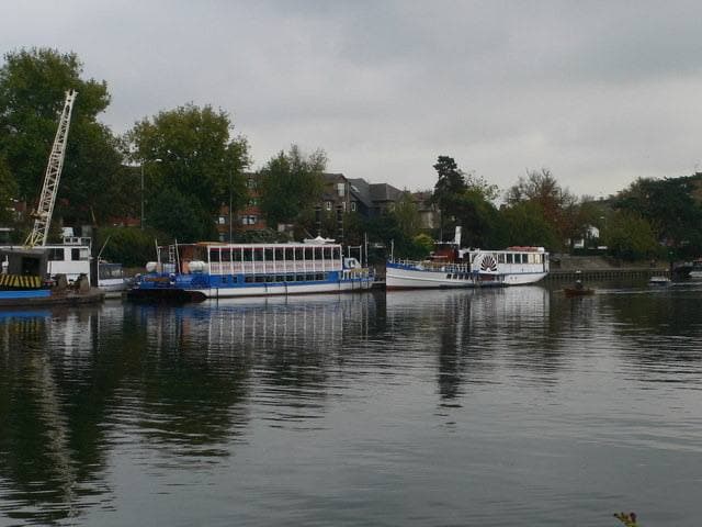 Two white river boats moored on the Thames under a grey sky