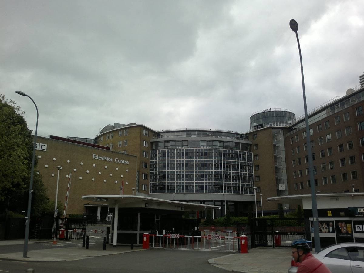 The curved front of BBC Television Centre behind its Wood Lane gates