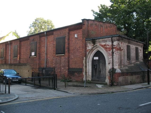 A low brick church building behind railings on a quiet London street