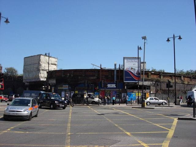 A large arched brick entrance to a disused railway yard on a city street