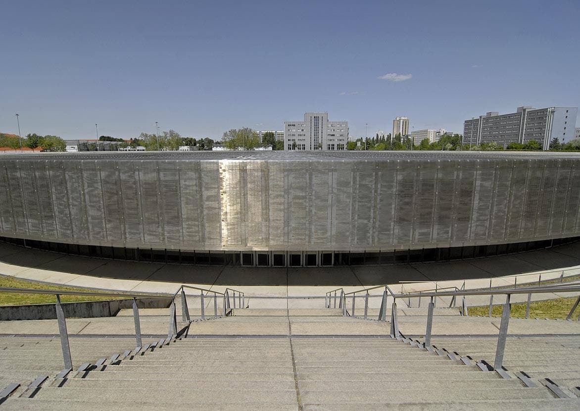 A low round building sunk into a grassy mound with a metal roof