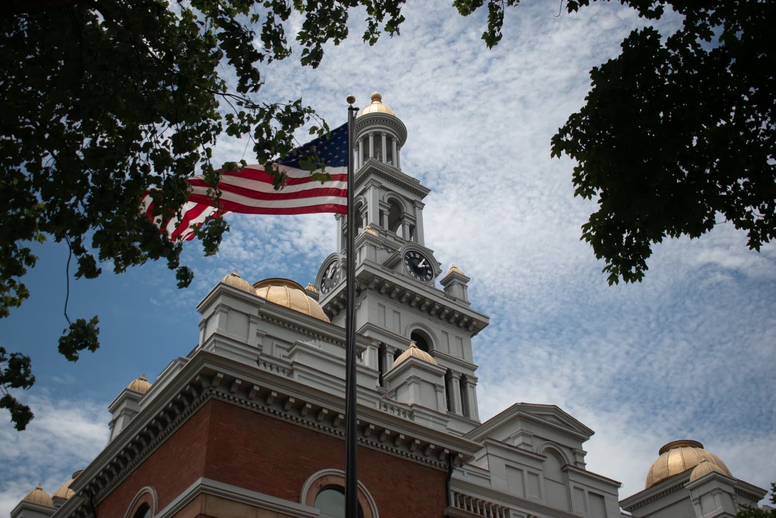 A red-brick courthouse with a clock tower and a flag
