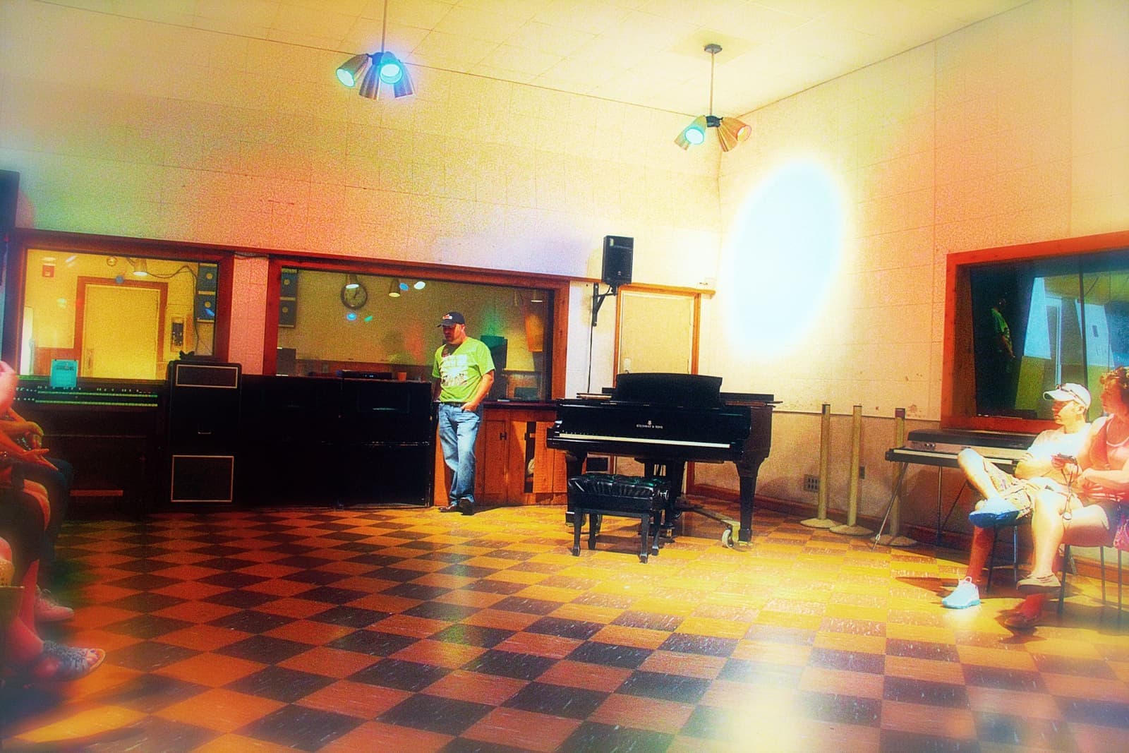 A recording room with a piano and microphones under coloured lights