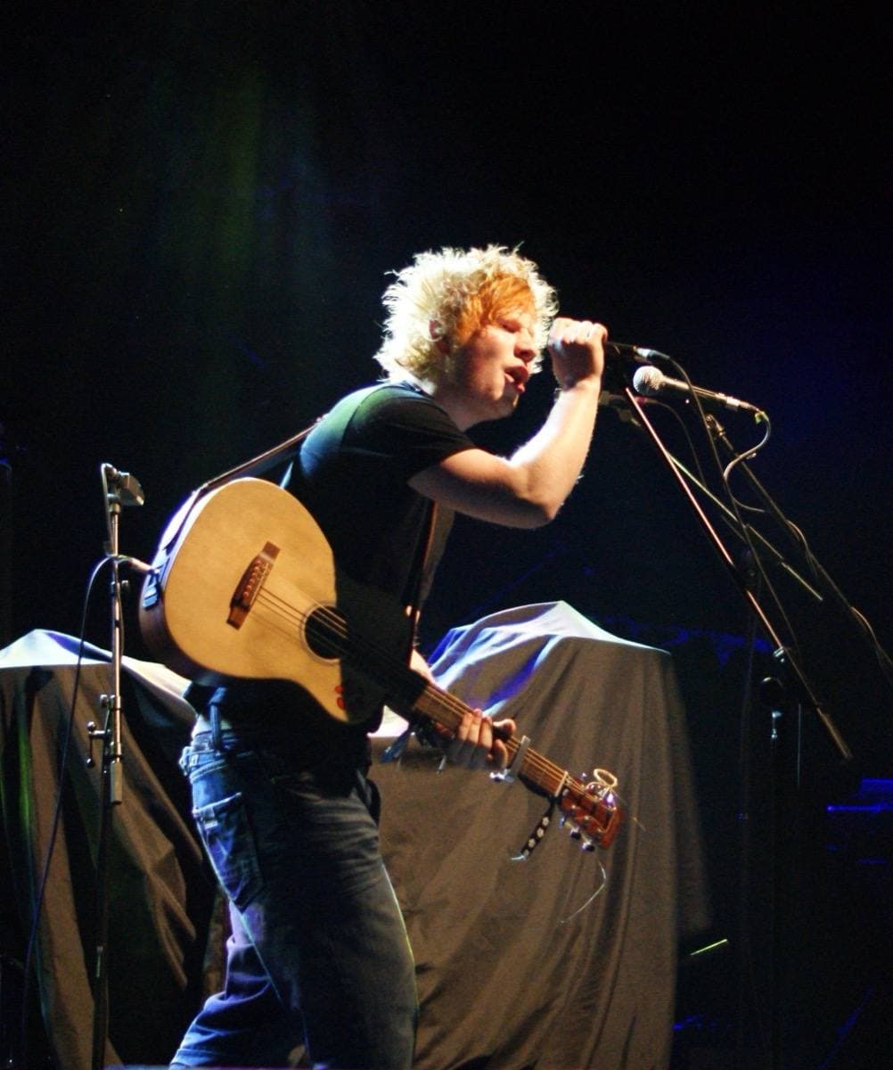 Ed Sheeran on stage with an acoustic guitar in 2011