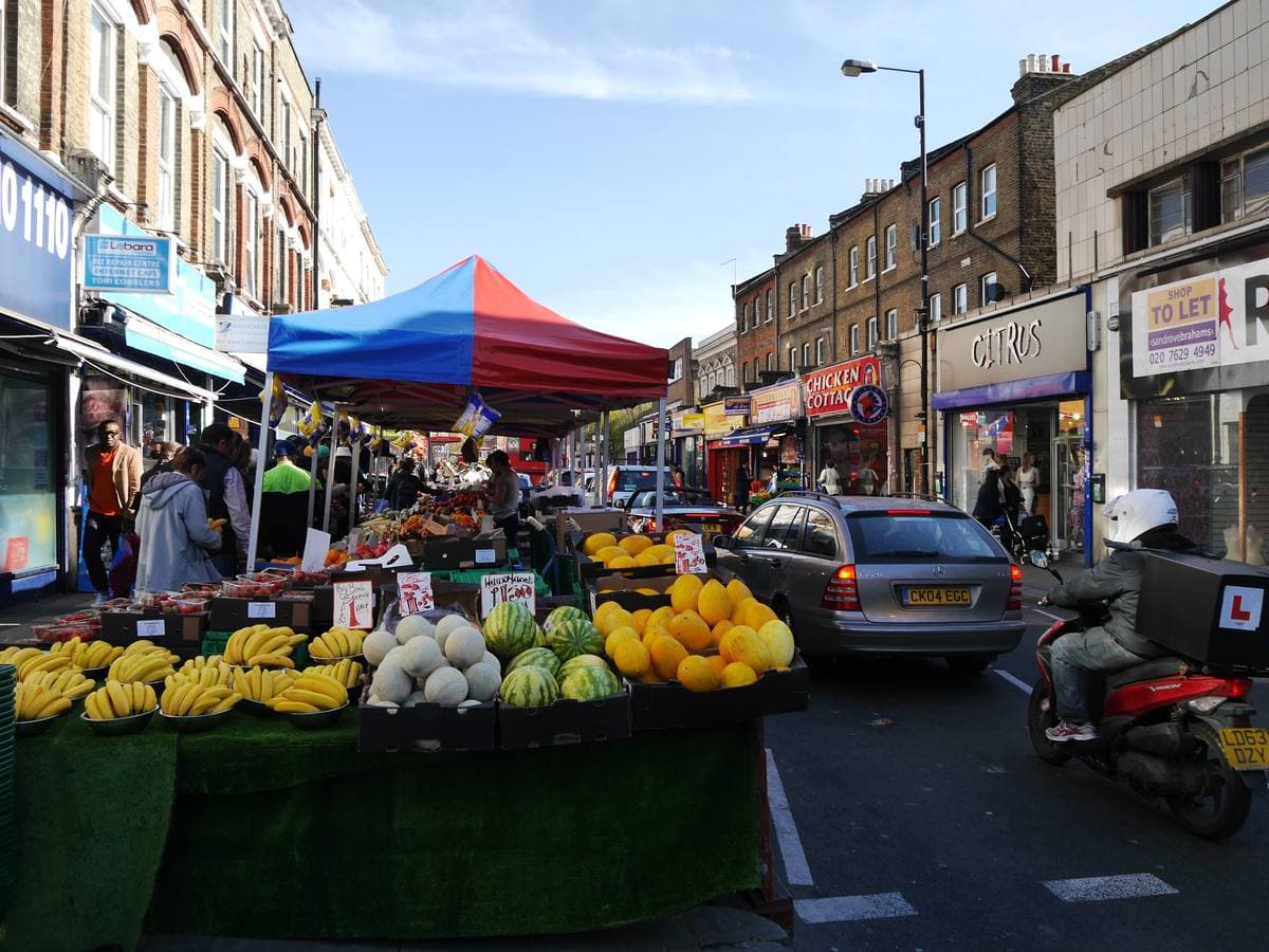 Market stalls with awnings along a busy London shopping street