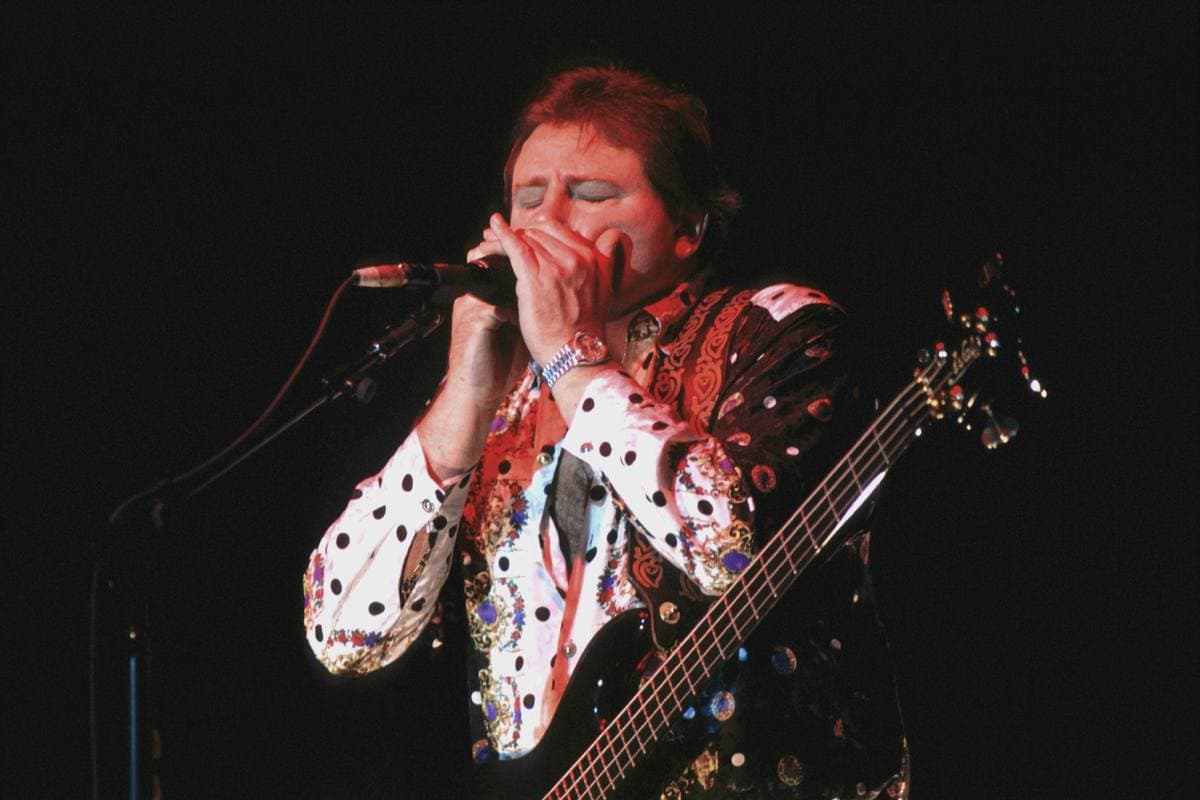 Greg Lake singing and playing bass under stage lights