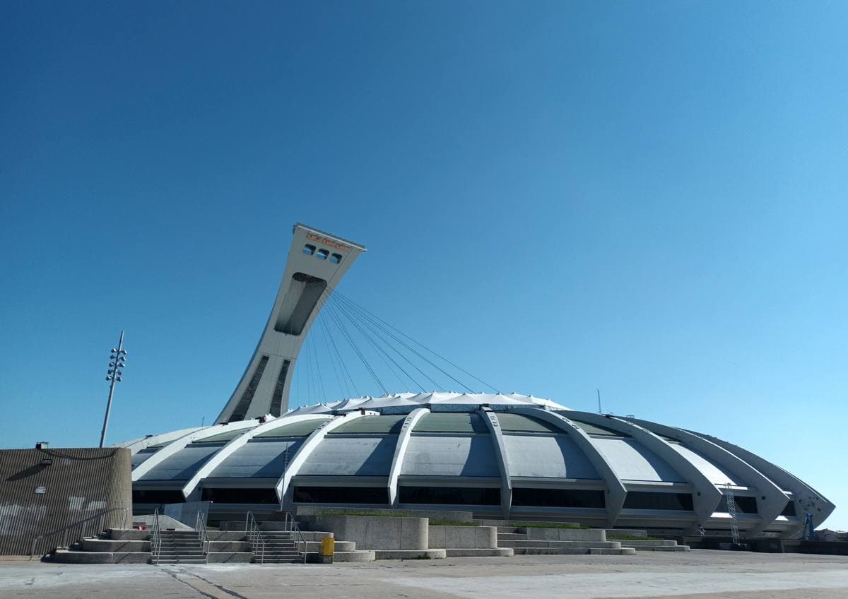 A huge oval concrete stadium with a tall leaning tower over it