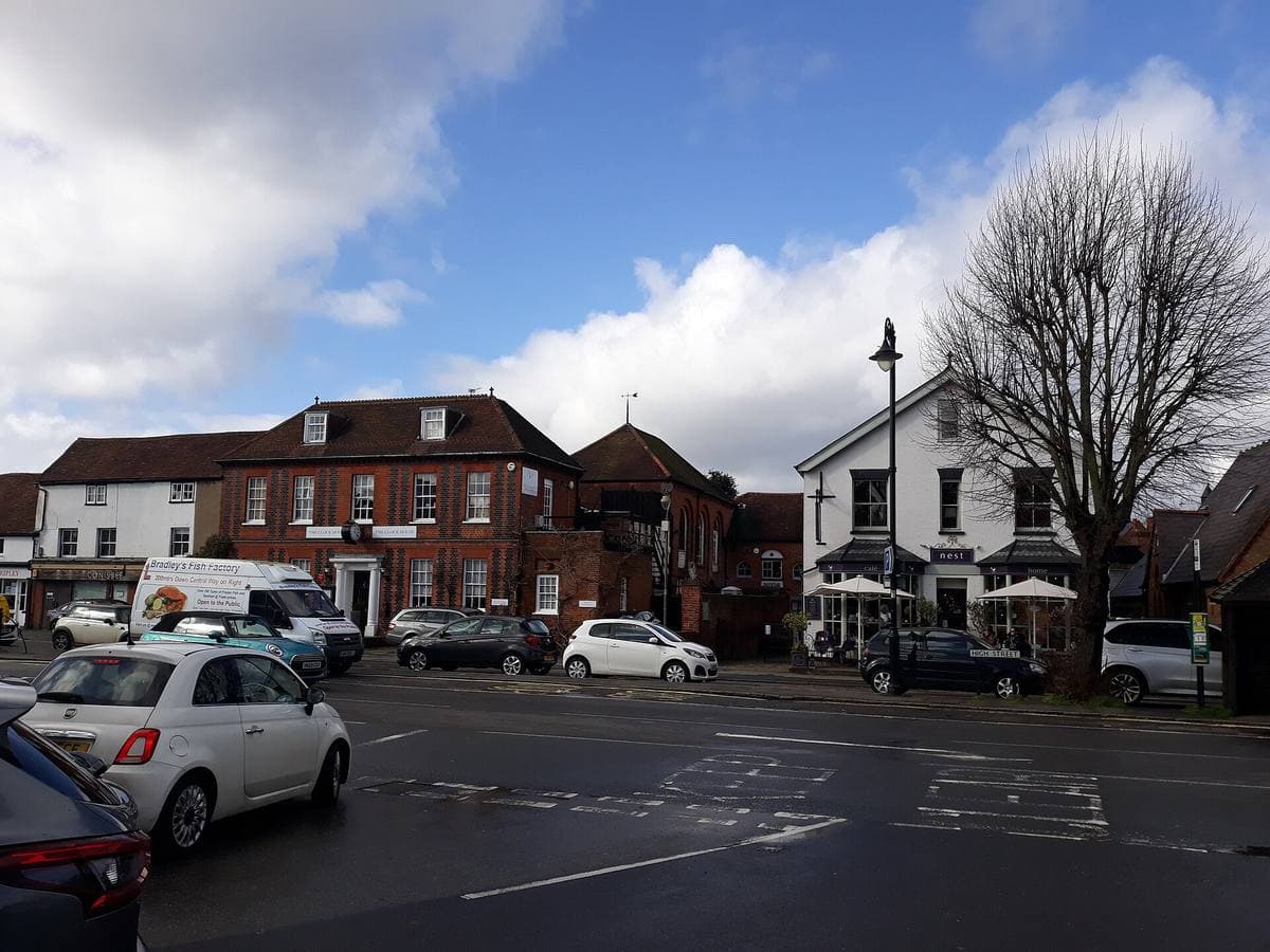 A village high street of old brick and timber buildings with a clock house