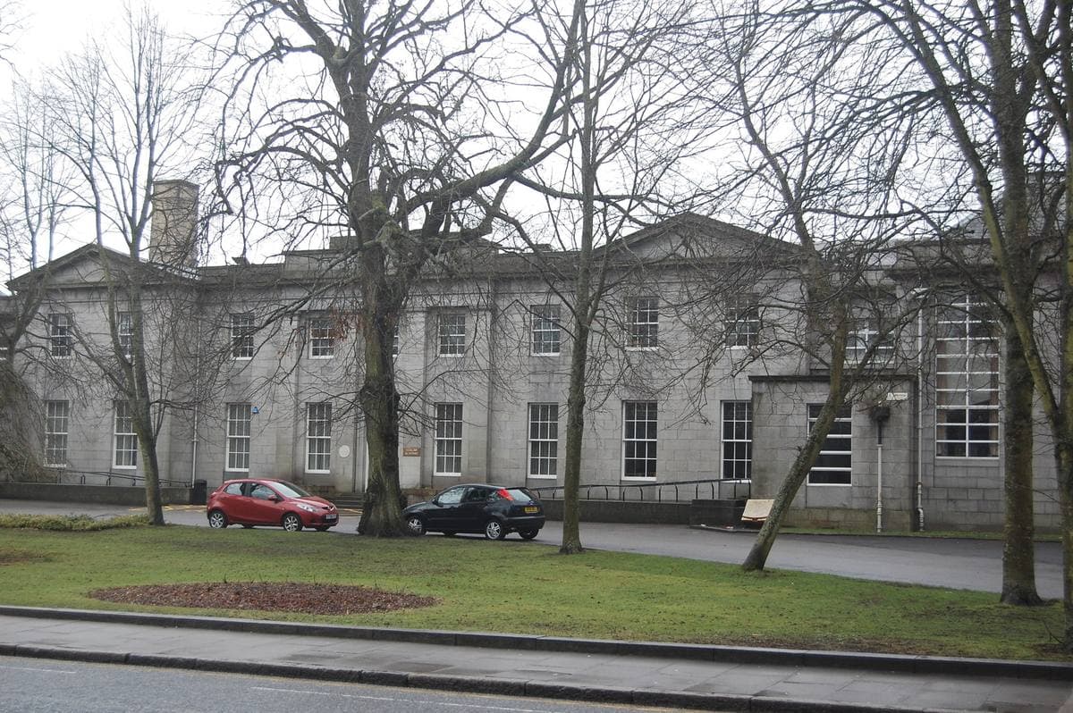 A granite school building behind railings in Aberdeen