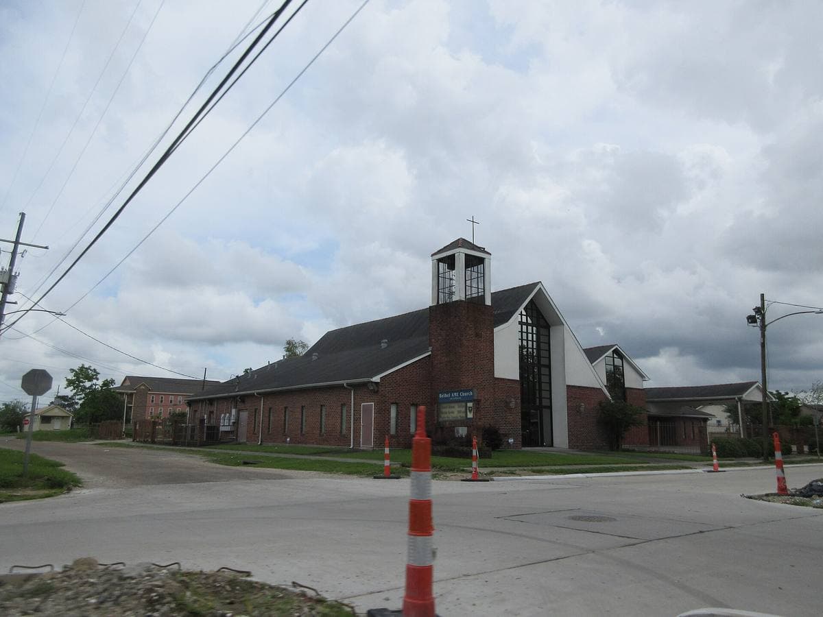 A wide Lower Ninth Ward street with a brick church and low houses
