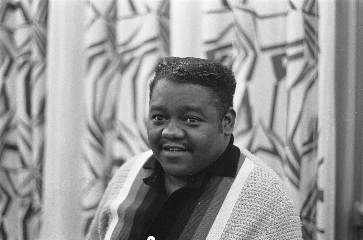 Fats Domino smiling over his shoulder in a striped cardigan