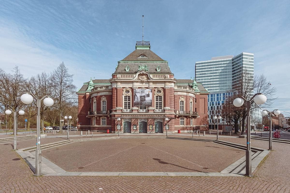 A red-brick and sandstone concert hall across a paved square