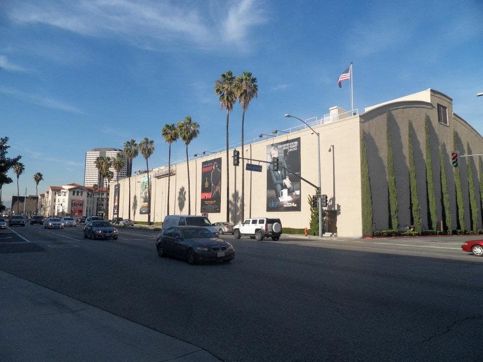 Tall cream soundstage walls and palm trees along a wide Burbank road