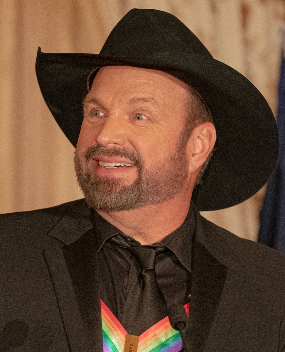 Garth Brooks in a black cowboy hat and dark jacket at a formal dinner